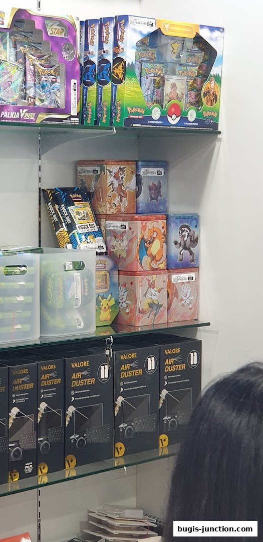 Shelves stocked with Pokemon trading card game products and air dusters.
