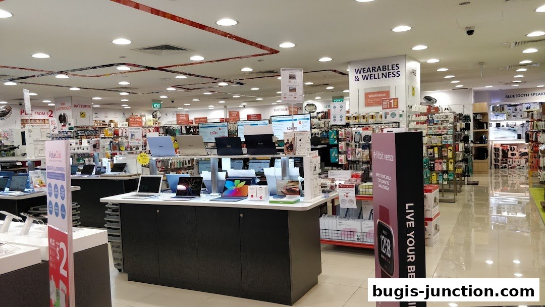 Interior view of a well-lit electronics store showcasing laptops, wearables, and accessories.