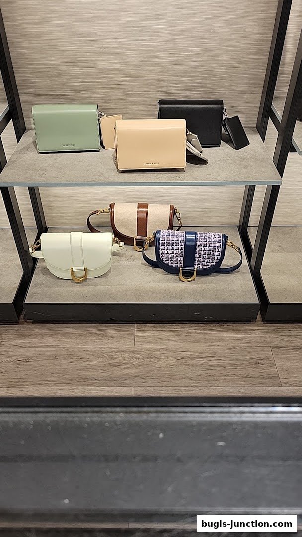 A display of various Charles & Keith handbags on shelves, showcasing different styles and colors.