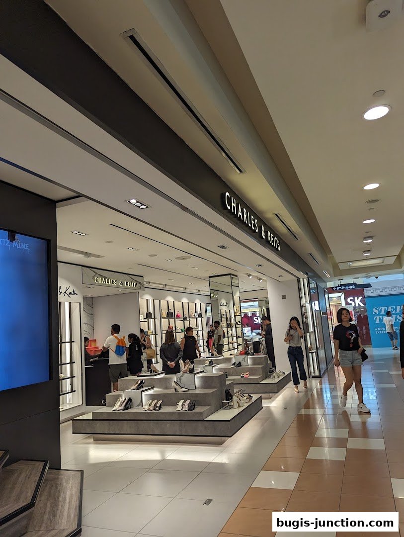Interior view of a Charles & Keith store showcasing shoes and handbags with customers browsing.