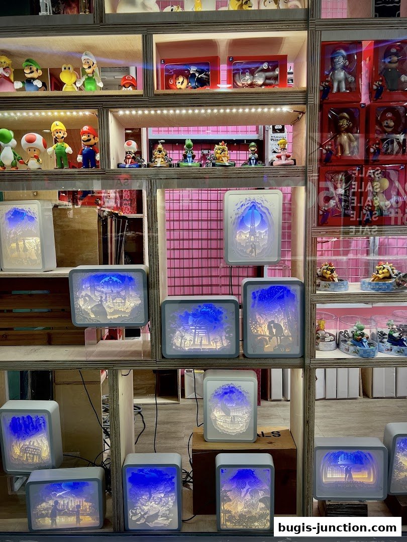 A shop window displaying illuminated paper-cut light boxes and various character figurines.