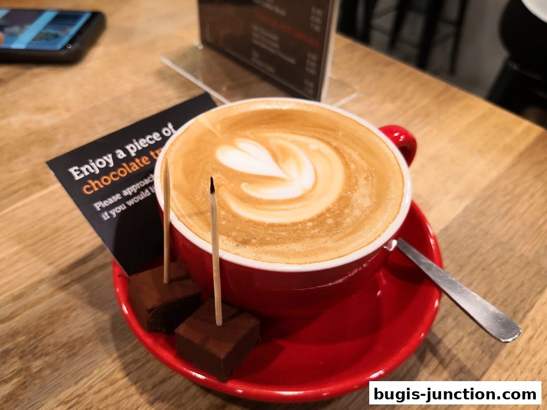 A red cup of latte with latte art, accompanied by chocolate squares and a small card.