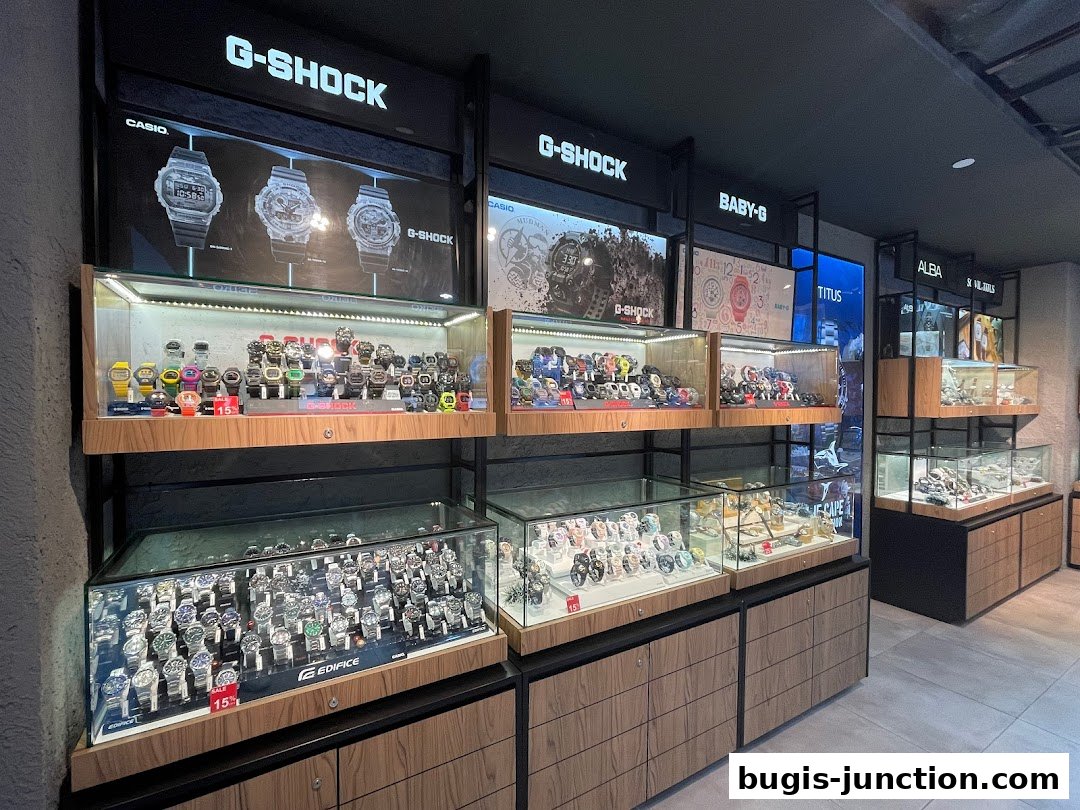 A well-lit display of various G-Shock, Baby-G, Alba, and Titus watches in glass cases.