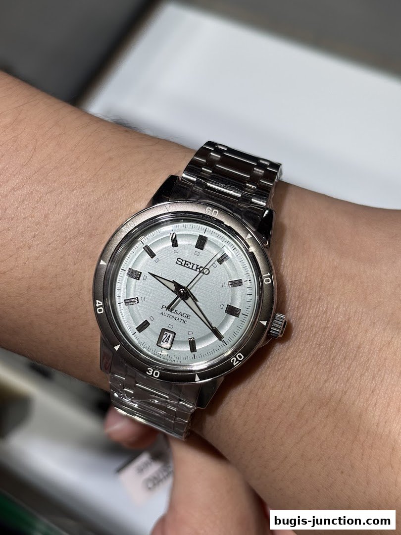 A close-up shot of a silver Seiko Presage automatic watch on a person's wrist.