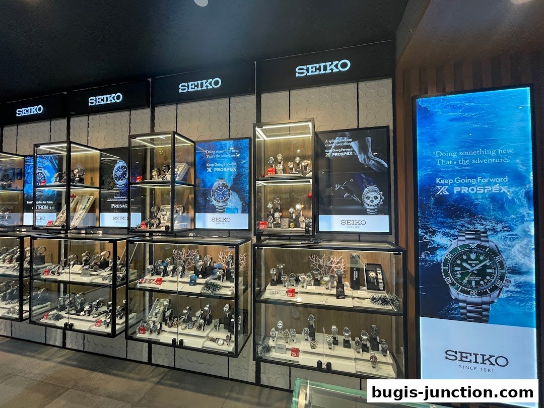 A well-lit display of Seiko watches in glass cases, with promotional posters.