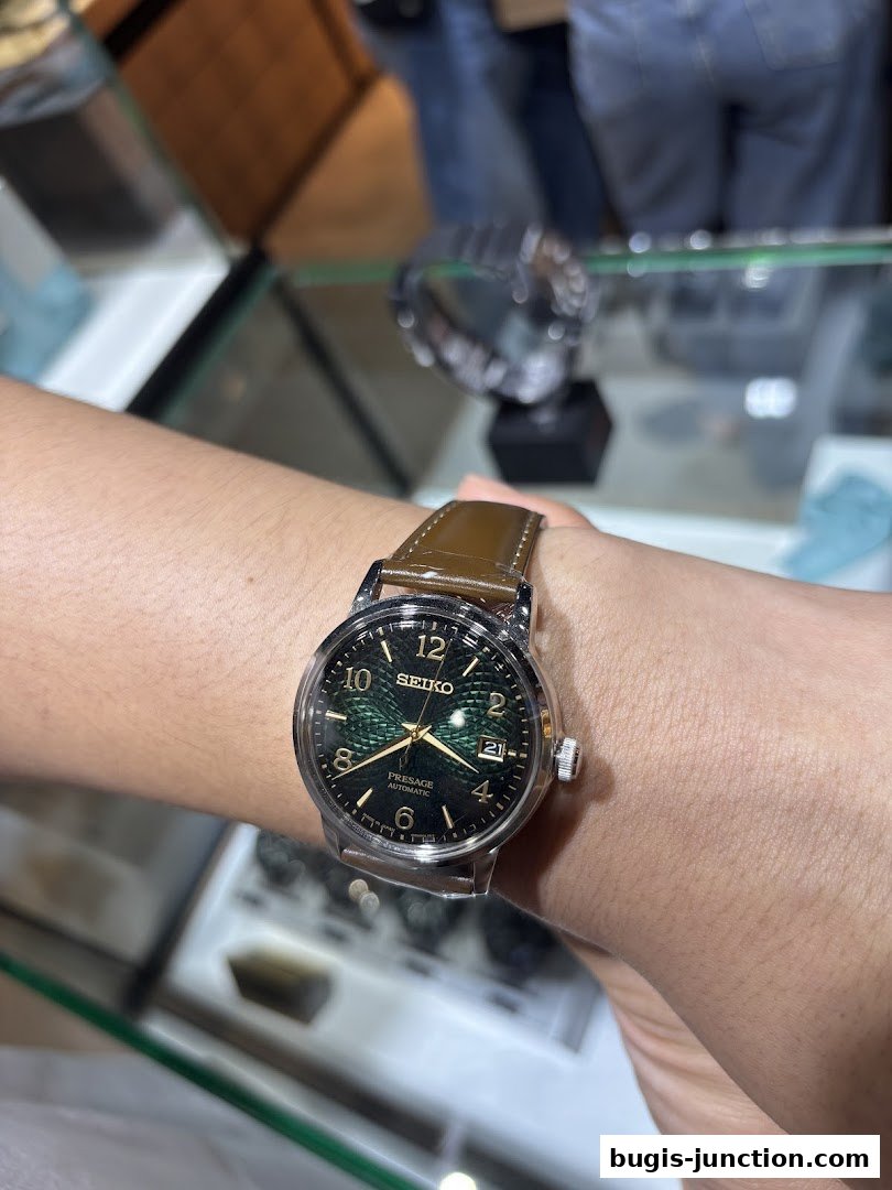 A person is wearing a Seiko Presage automatic watch with a green dial and brown leather strap.