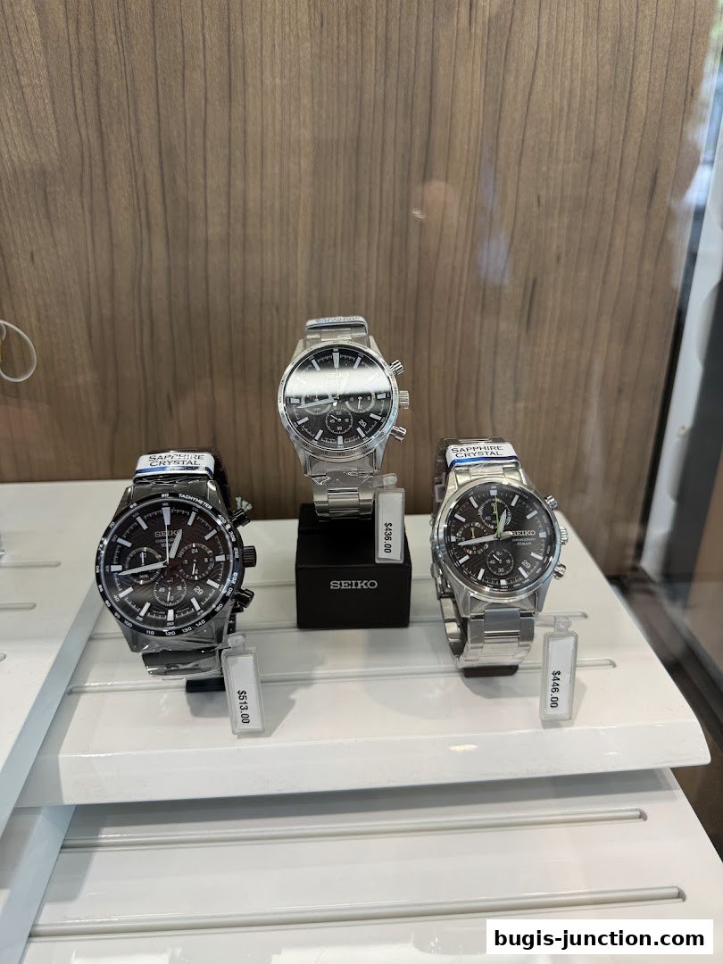Three Seiko watches displayed on a white shelf with price tags.