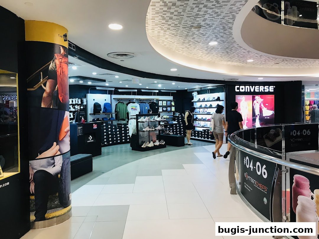 Interior view of a Converse store showcasing shoes, apparel, and accessories with customers browsing.