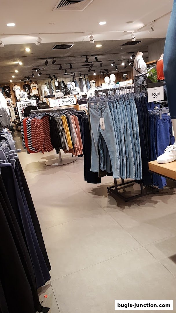 Interior view of a clothing store with racks of jeans, shirts, and mannequins.