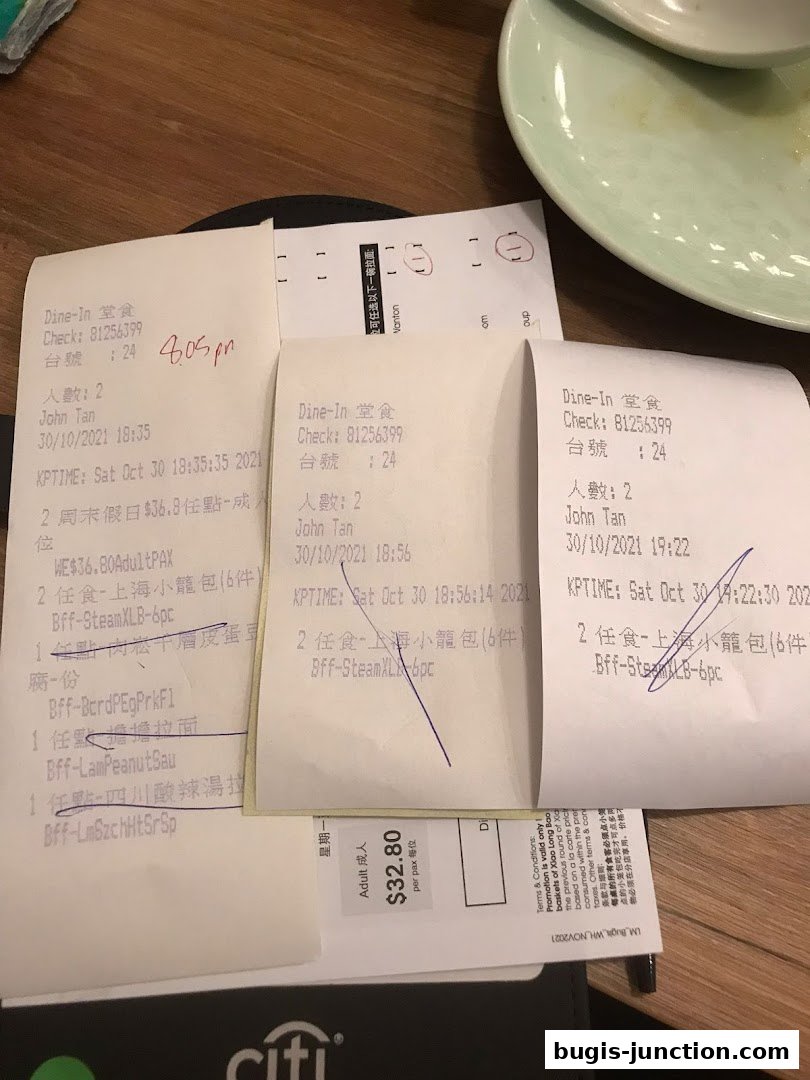 Several receipts from Crystal Jade La Mian Xiao Long Bao are laid out on a wooden table.