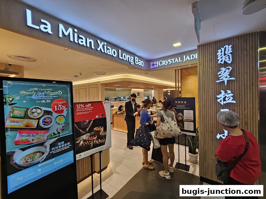 The entrance of Crystal Jade La Mian Xiao Long Bao restaurant with promotional displays.