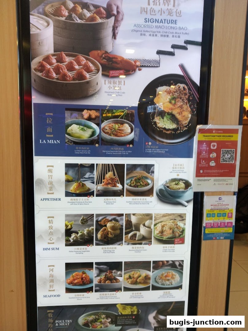 A menu board for Crystal Jade La Mian Xiao Long Bao, showcasing various dishes like dumplings and noodles.
