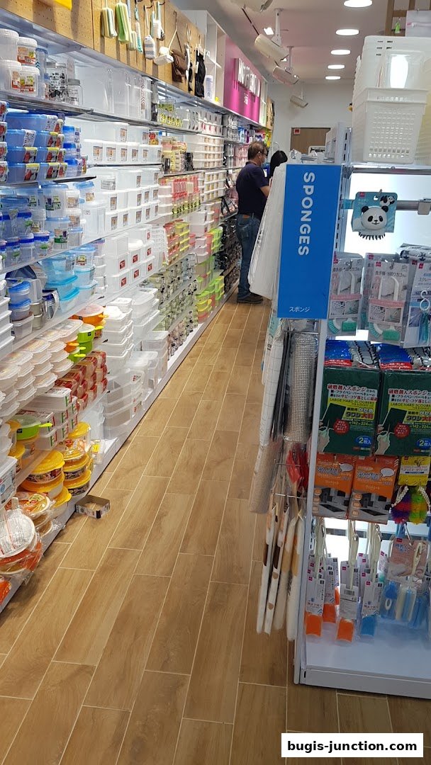 A wide aisle inside a Daiso store, showcasing shelves stocked with various storage containers and household items.
