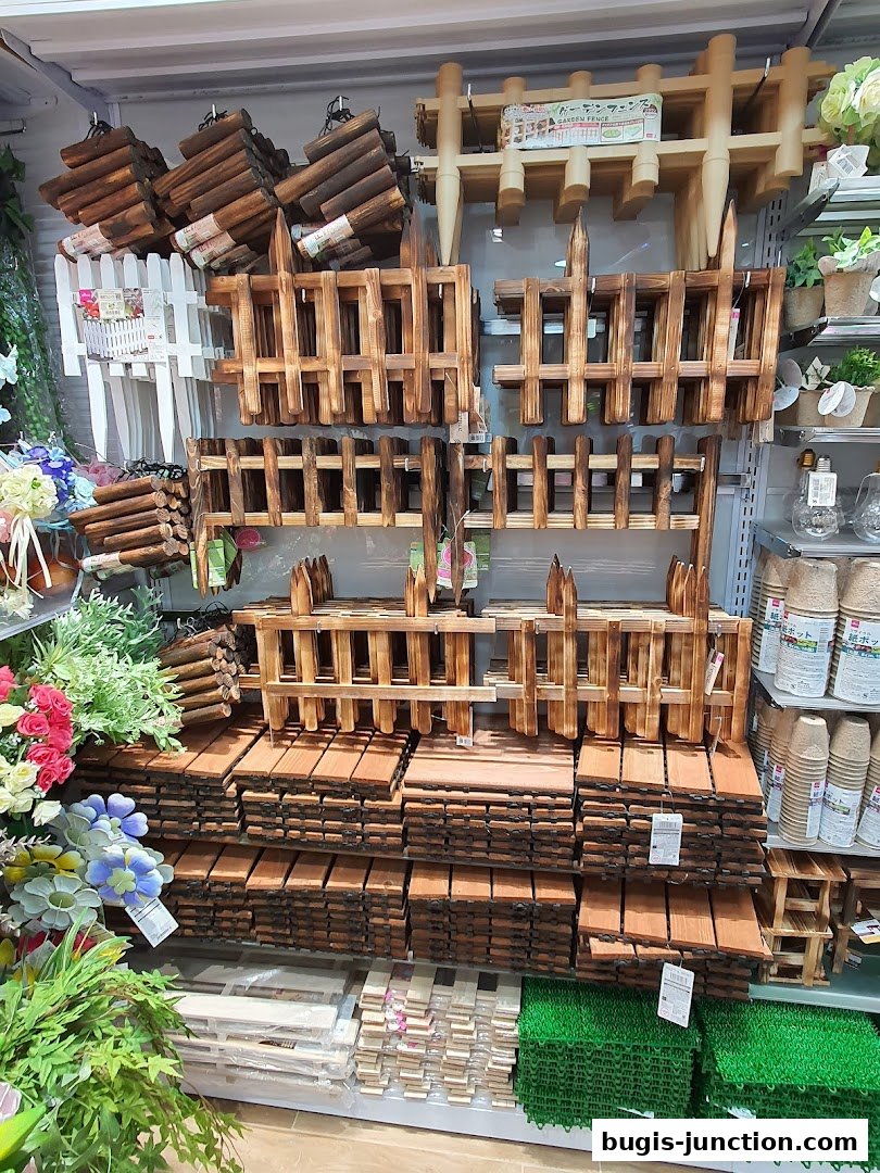 A display of wooden garden fences, planters, and artificial plants.