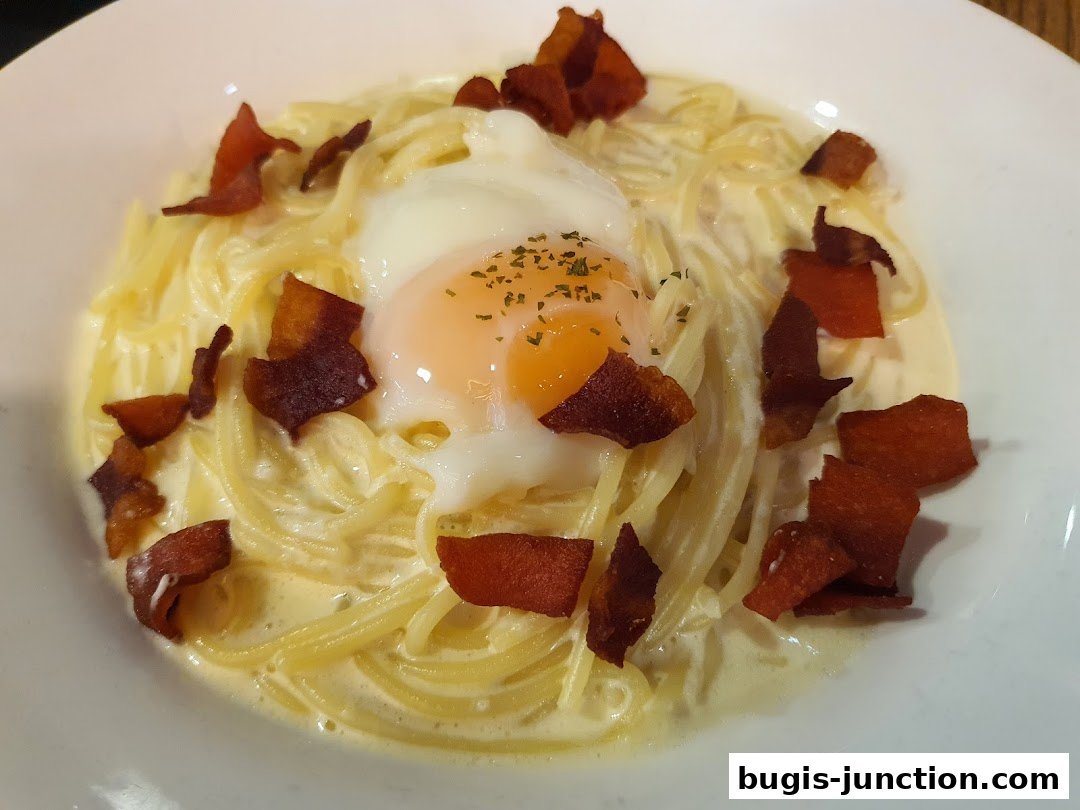 A close-up shot of a creamy pasta dish topped with crispy bacon and a perfectly poached egg.