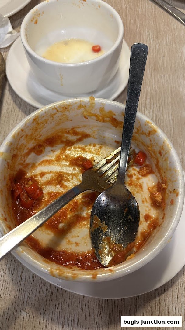 Close-up of dirty bowls with leftover food and cutlery after a meal.