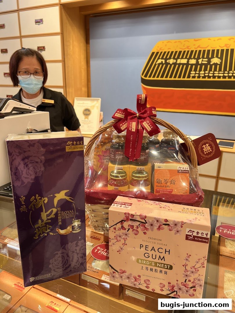 A staff member stands behind a counter with Eu Yan Sang products, including gift baskets and boxes.