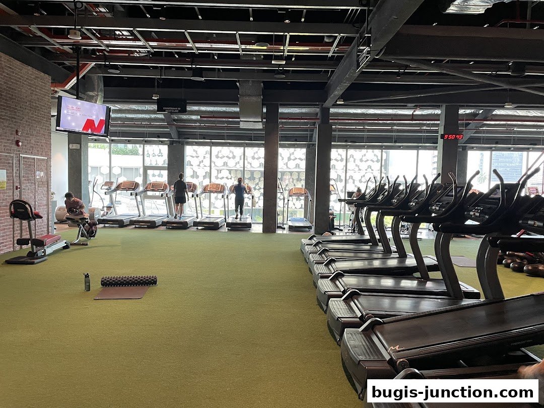 Interior view of a modern gym with treadmills, exercise bikes, and people working out.