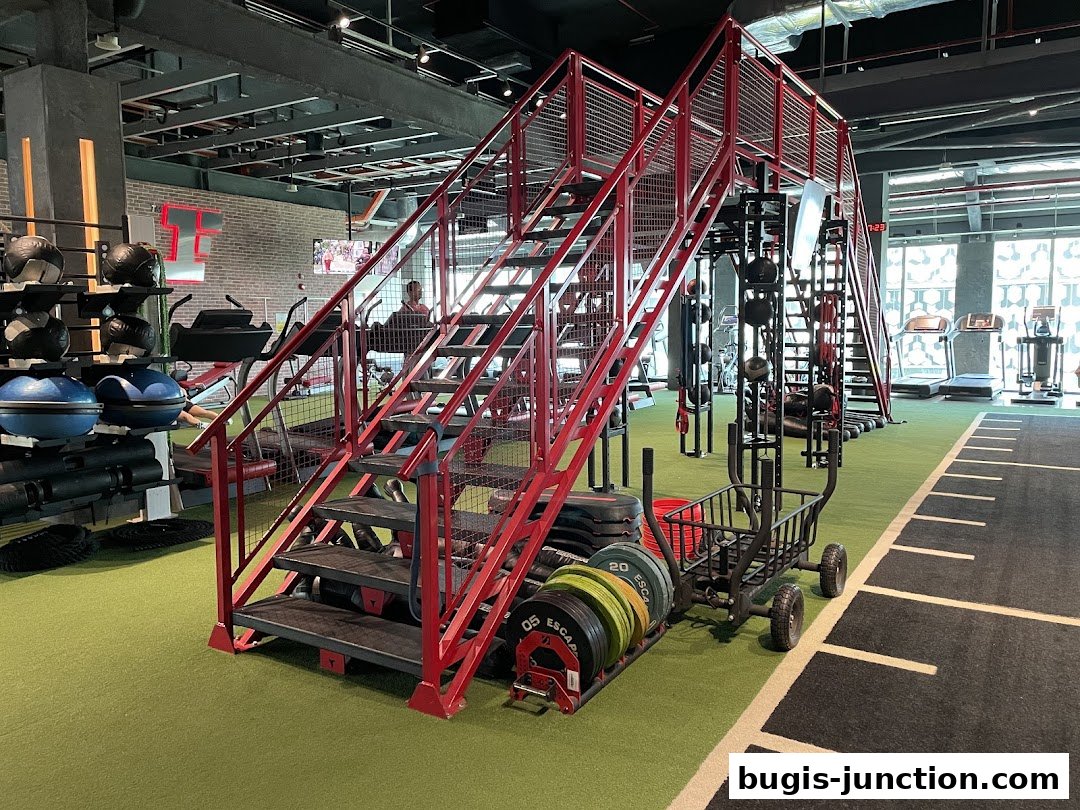 Interior of a modern gym with various exercise equipment, including stairs, weights, and treadmills.