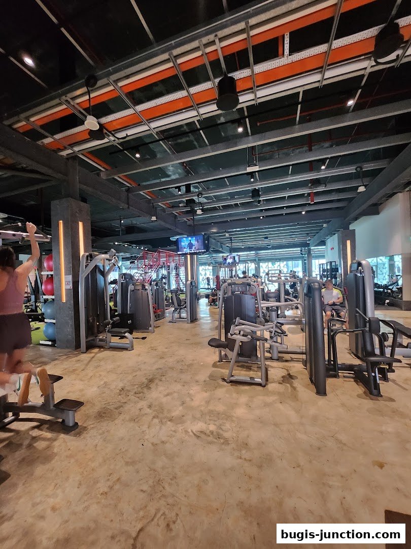 Interior view of a spacious gym with various weight machines and people working out.