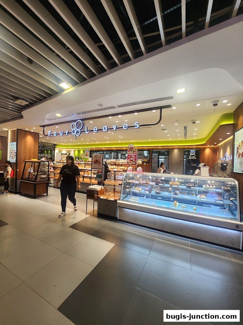 A bakery shop called Four Leaves with display cases filled with cakes and pastries.