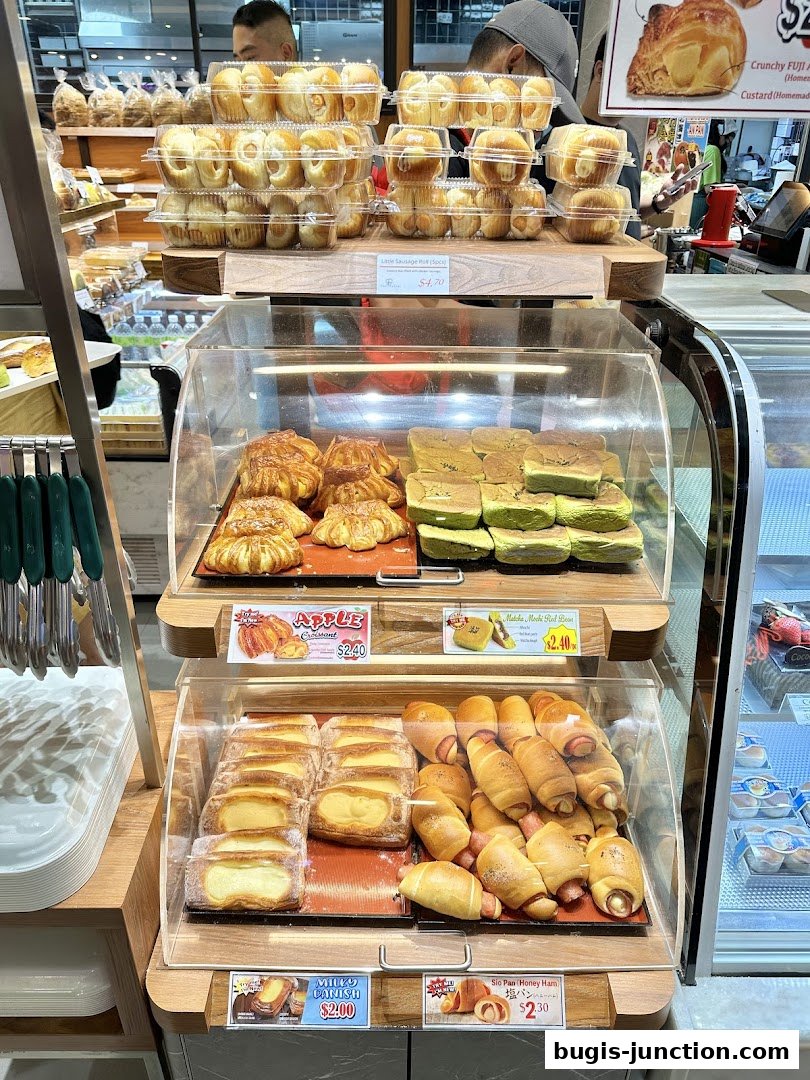 A display of freshly baked pastries and bread rolls at a bakery.