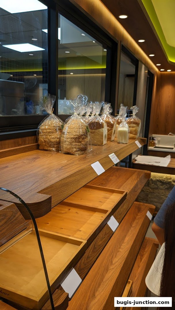Freshly baked loaves of bread are displayed on wooden shelves in a bakery.