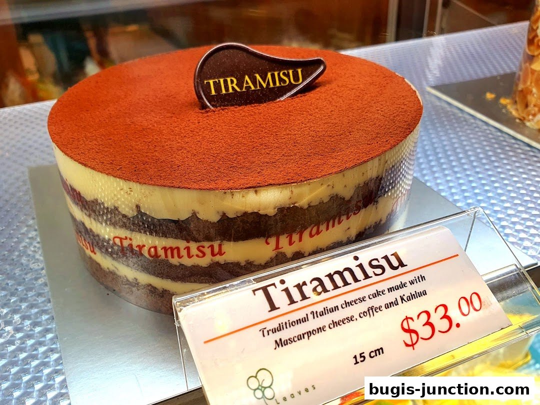 A delicious Tiramisu cake with a dusting of cocoa powder and a branded topper.