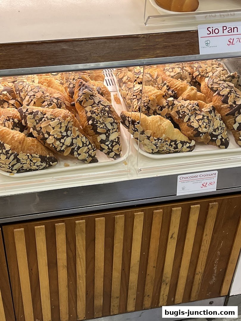 Display case filled with chocolate croissants topped with almonds.