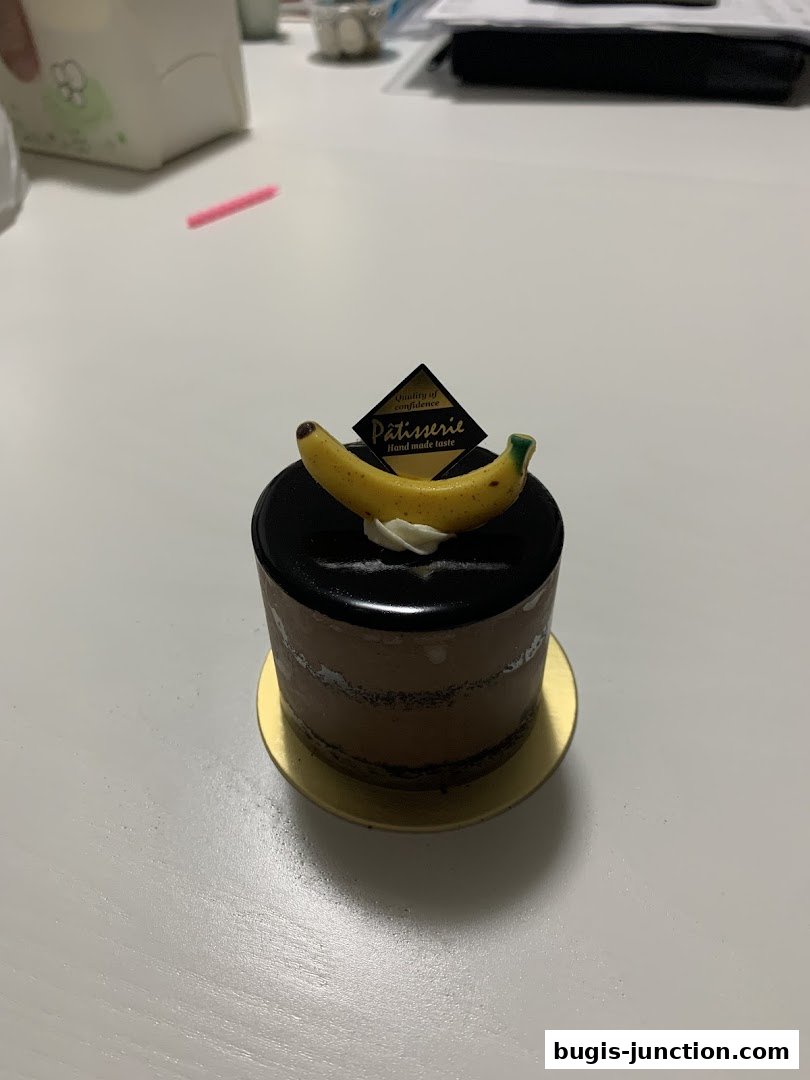 A chocolate cake with a banana decoration and a 'Patisserie' label.