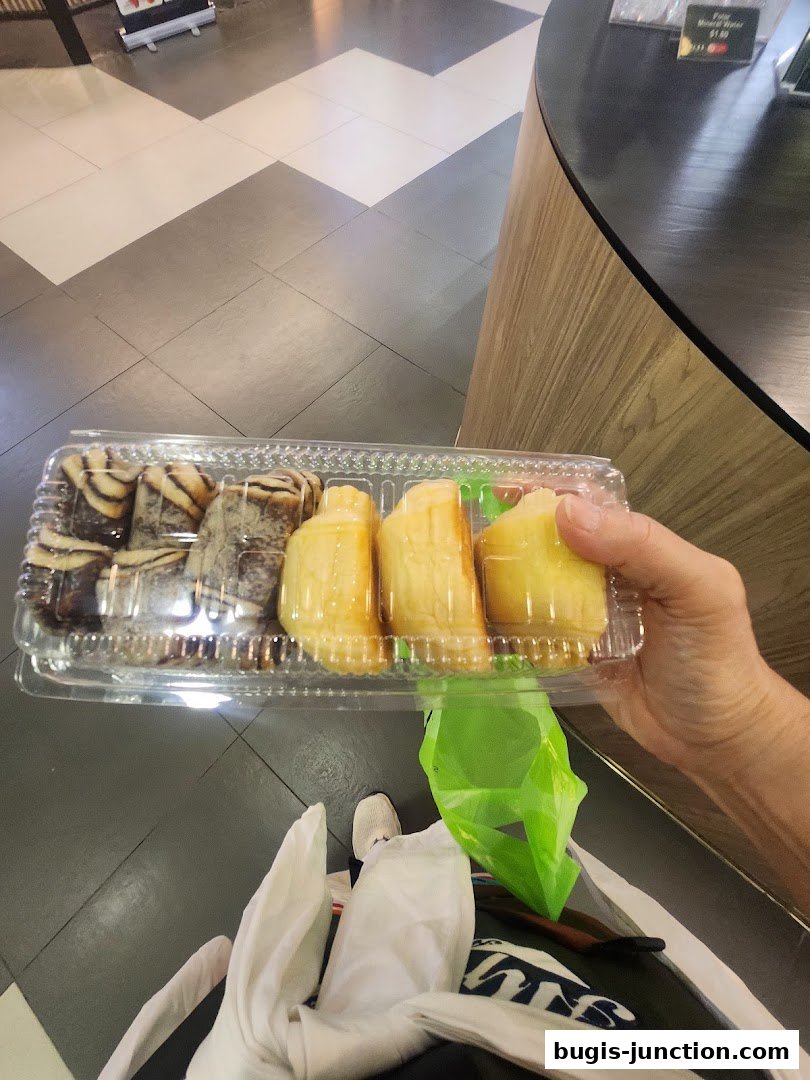 A person holds a clear plastic container filled with assorted pastries from Four Leaves.