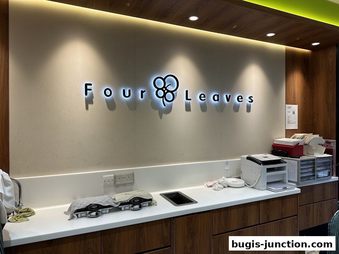 The illuminated "Four Leaves" logo is displayed above a counter with printers and supplies.