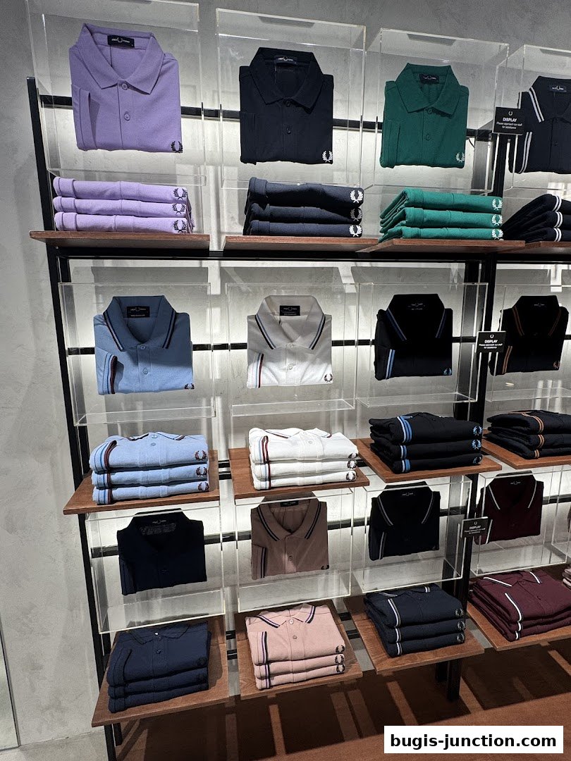 Neatly folded Fred Perry polo shirts displayed in various colors on shelves.