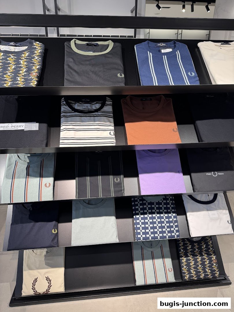 Neatly folded Fred Perry t-shirts displayed on shelves in a retail store.