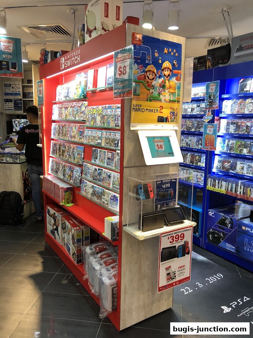 A GameMartz store display featuring Nintendo Switch consoles and games, with a Super Mario Maker 2 promotion.