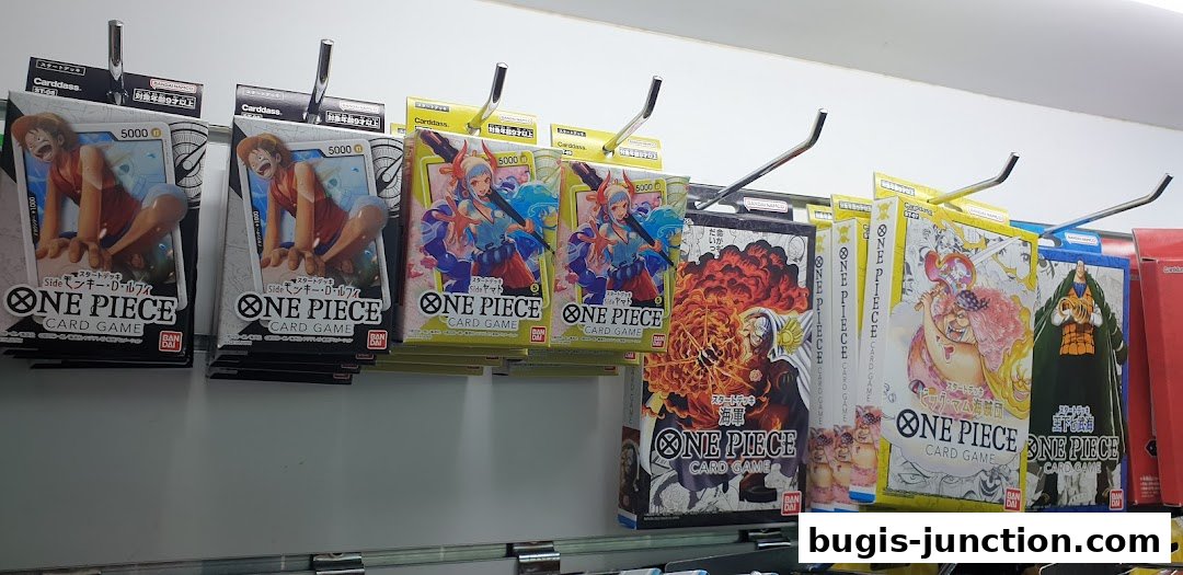 A display of various One Piece card game booster packs and starter decks on shelves.