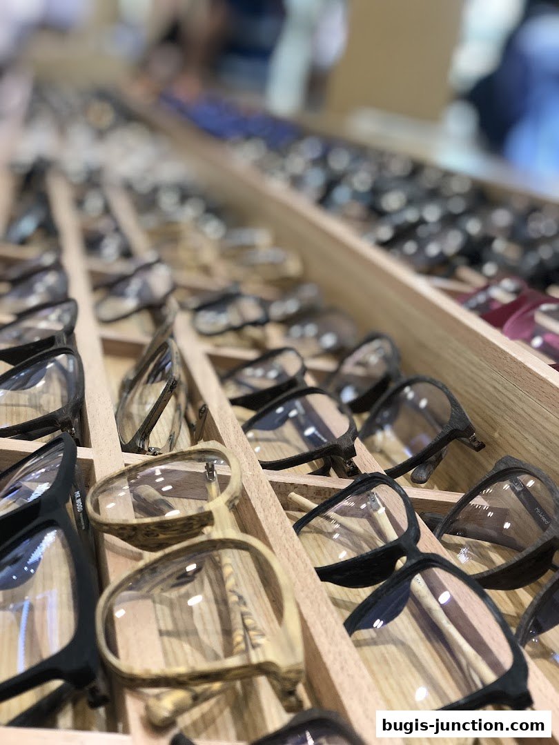 A close-up view of a display of various eyeglasses with wooden frames.