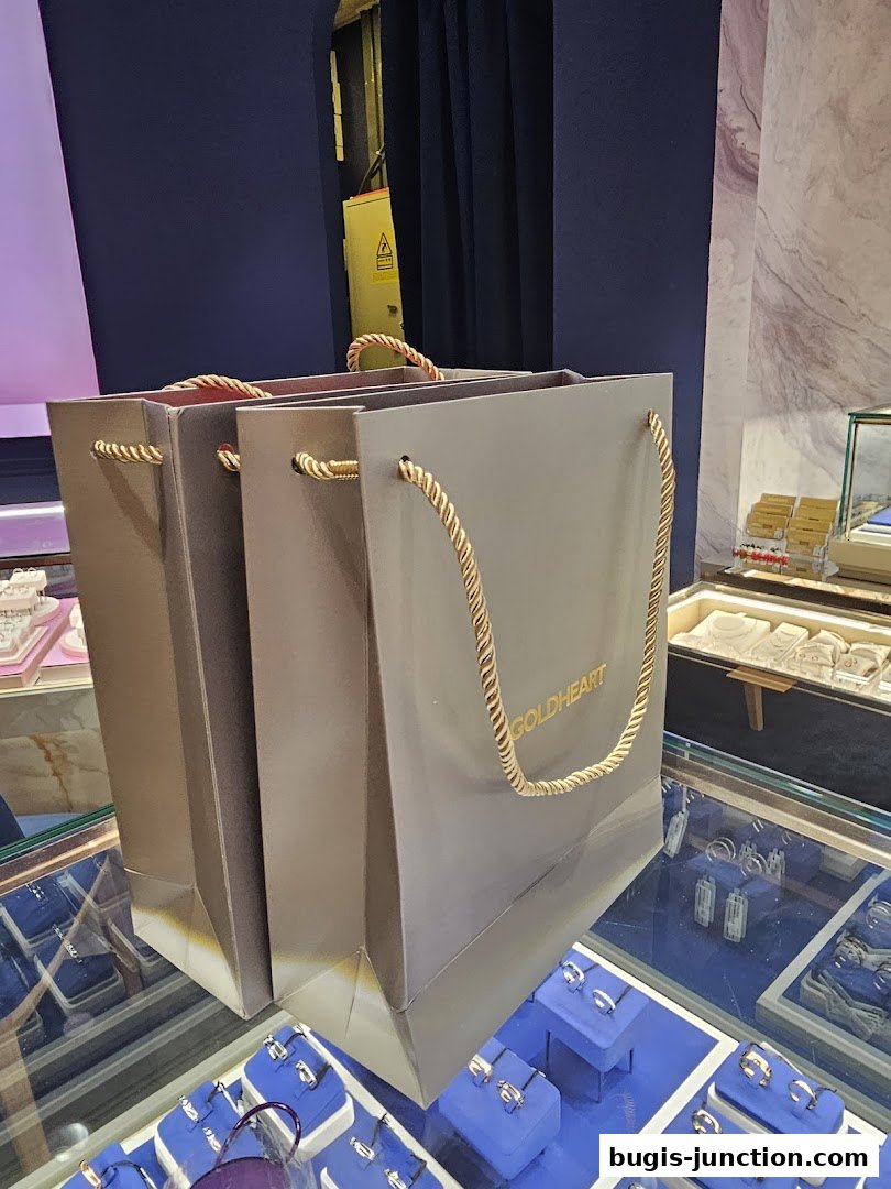 Goldheart Jewelry shopping bags displayed in front of a jewelry display case.