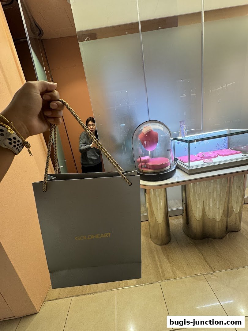 A person holds a Goldheart Jewelry shopping bag in front of a display case.