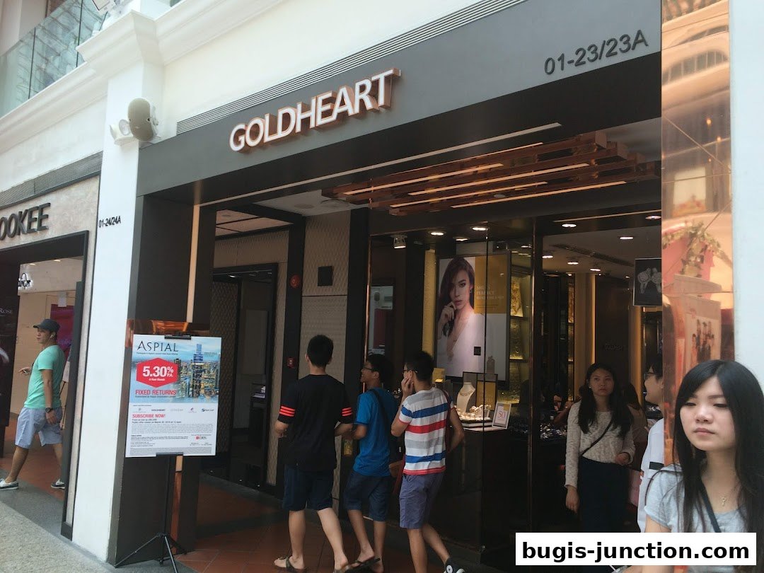 The Goldheart Jewelry store entrance with people walking by and a promotional poster.