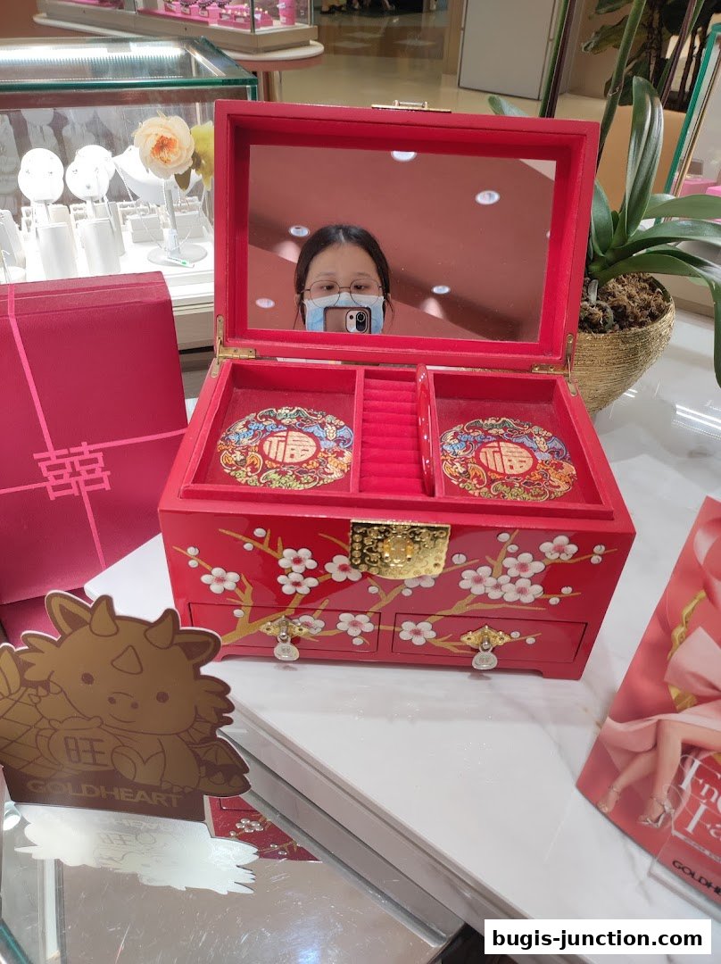 A red jewelry box with floral designs and a mirror reflecting a person.