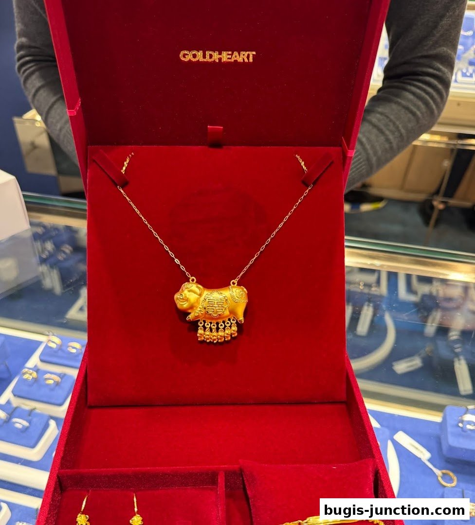 A gold pig pendant necklace displayed in a red jewelry box at Goldheart Jewelry.