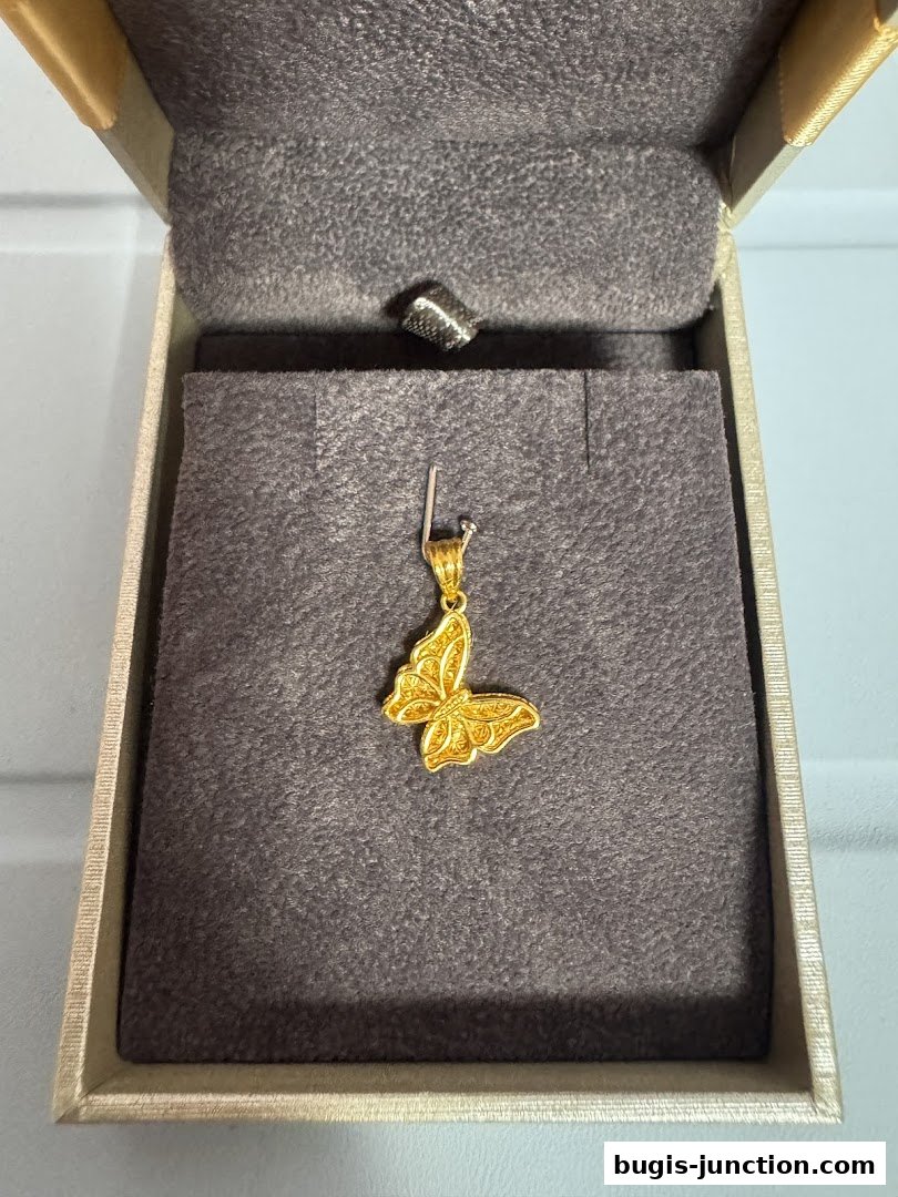 A delicate gold butterfly pendant displayed in a jewelry box.