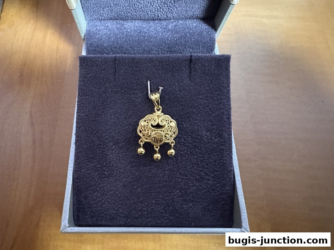A close-up of a gold pendant with intricate filigree and dangling beads in a jewelry box.