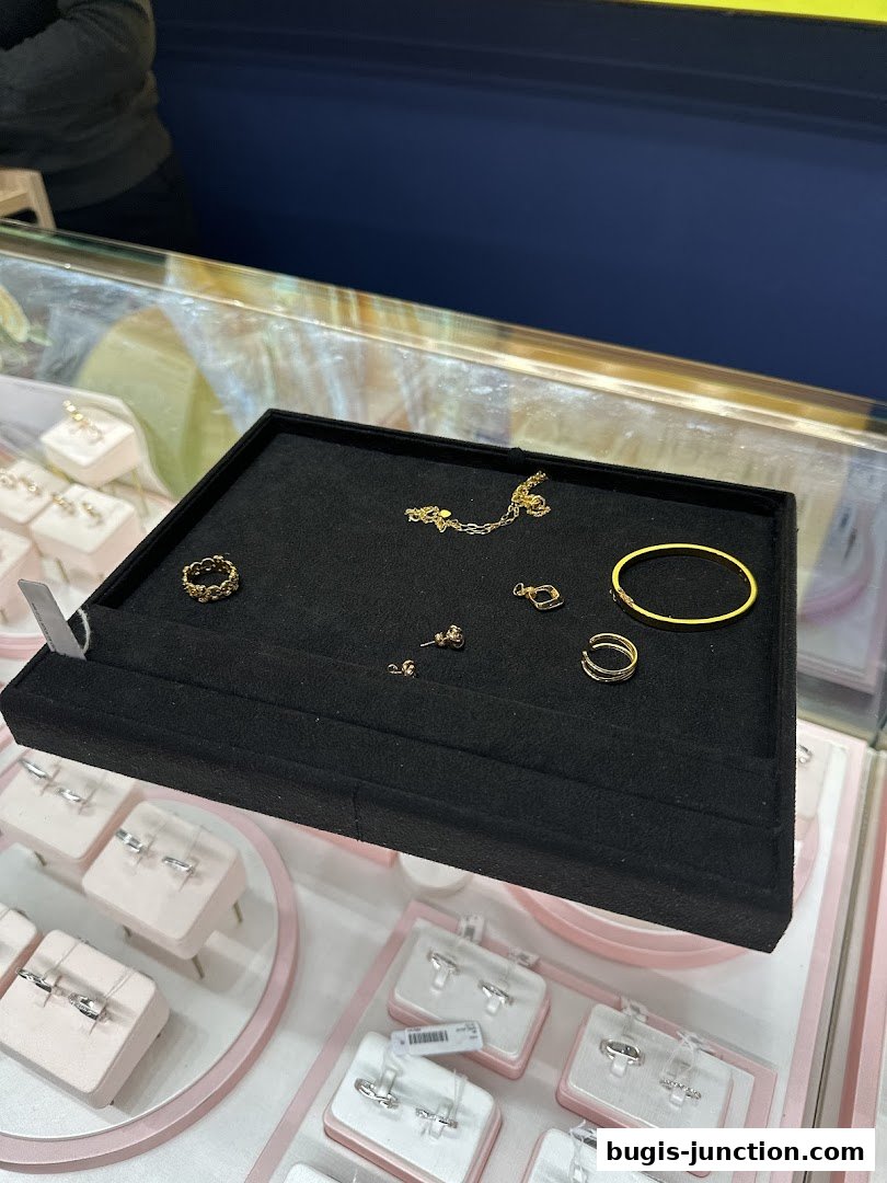 A display case filled with various gold jewelry, including rings, earrings, and a bracelet.
