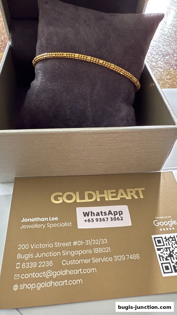 A gold bracelet displayed in a jewelry box with a business card.