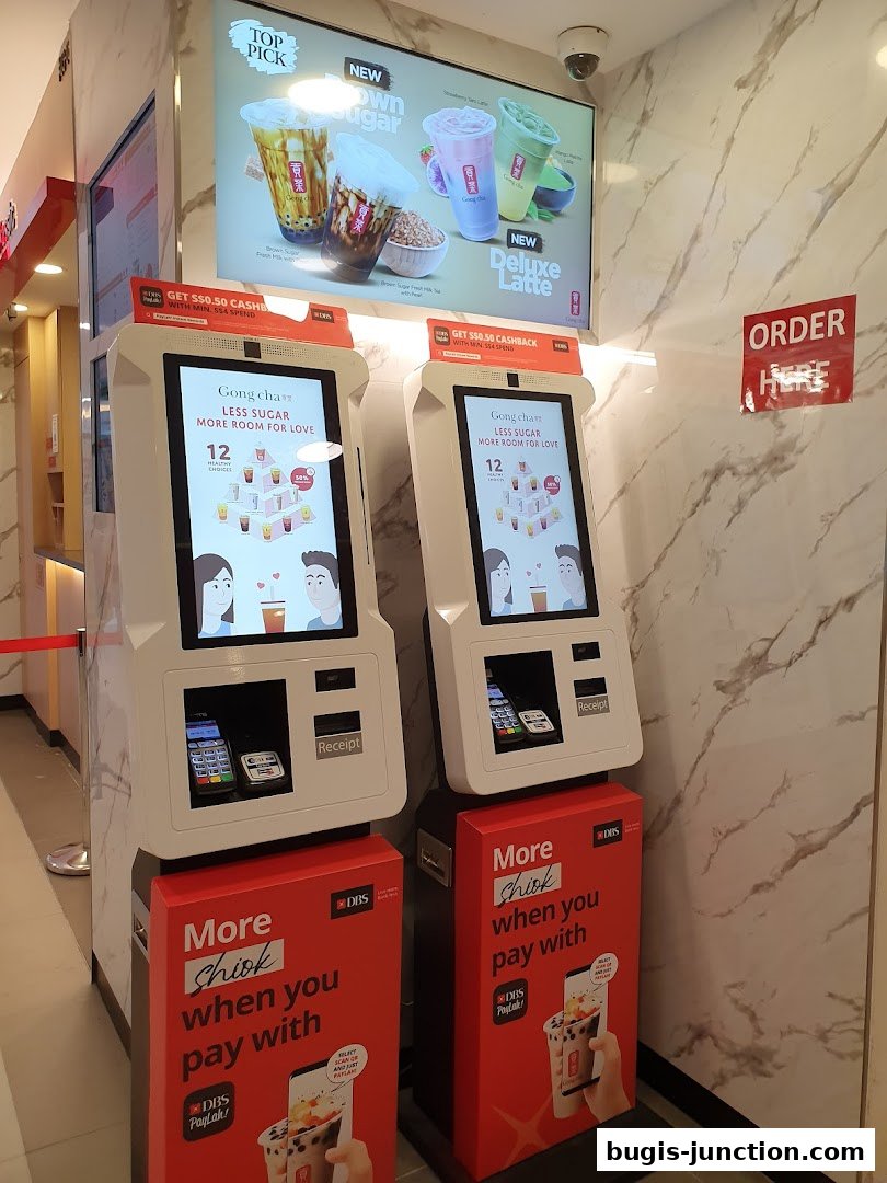 Two self-order kiosks and promotional displays for Gong Cha, a bubble tea shop.