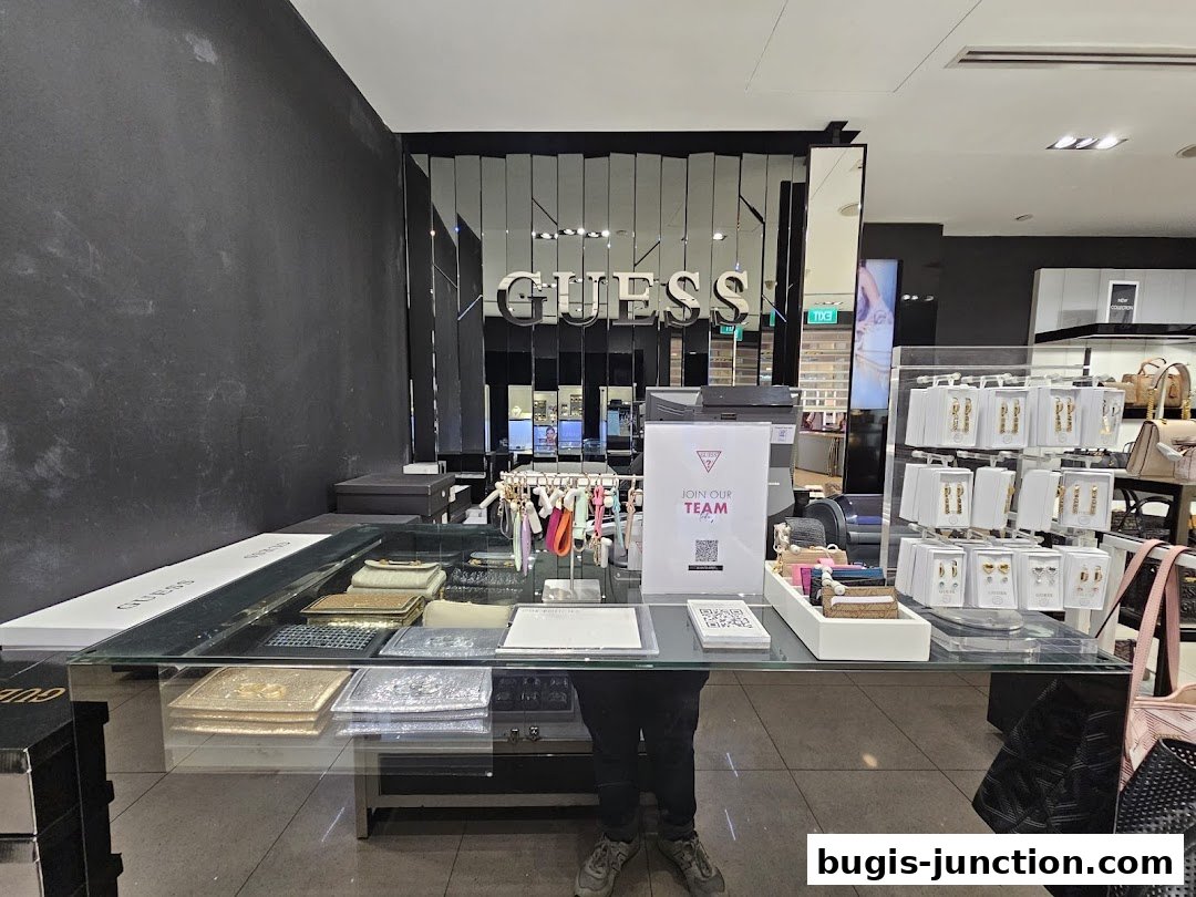 Interior view of a Guess Accessories store counter displaying wallets, keychains, and jewelry.