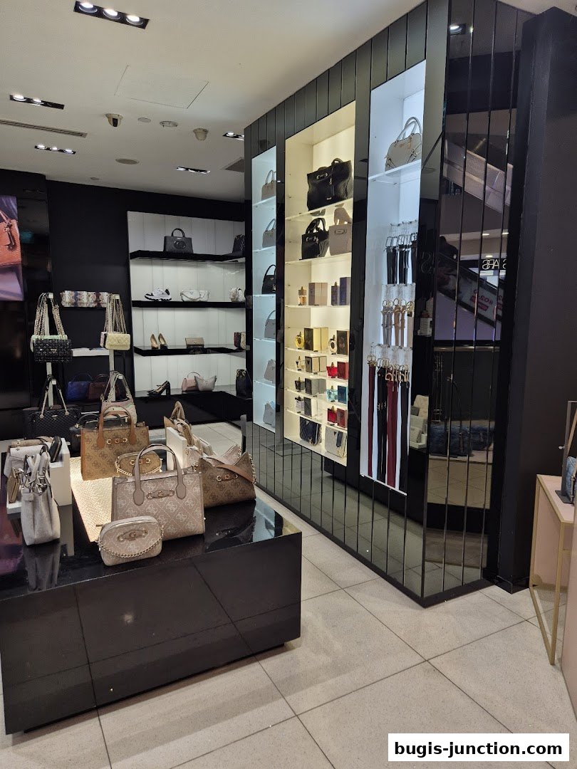 Interior view of a Guess Accessories store showcasing handbags and belts on display.