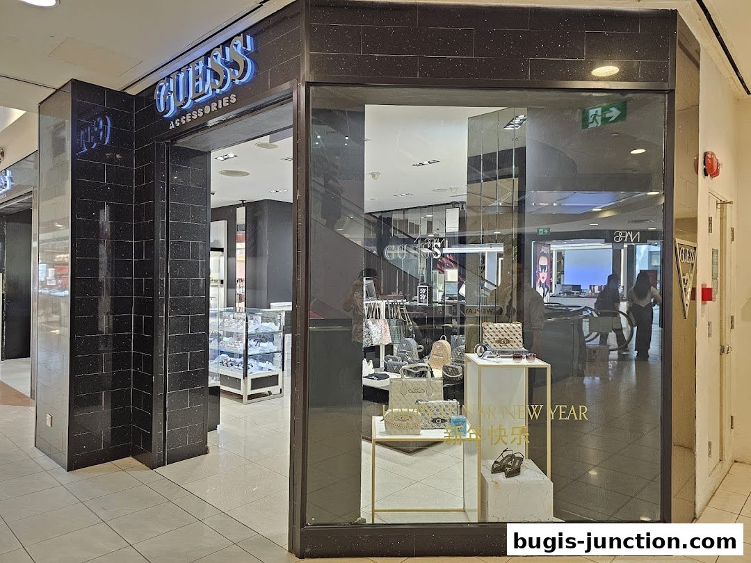 The entrance of a GUESS ACCESSORIES store with a display of handbags and shoes in the window.